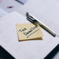 Sticky note on calendar highlighting tax deadline with pen nearby.